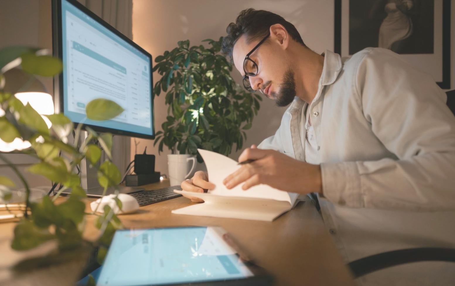 Person reviewing financial documents at desk with laptop and coffee